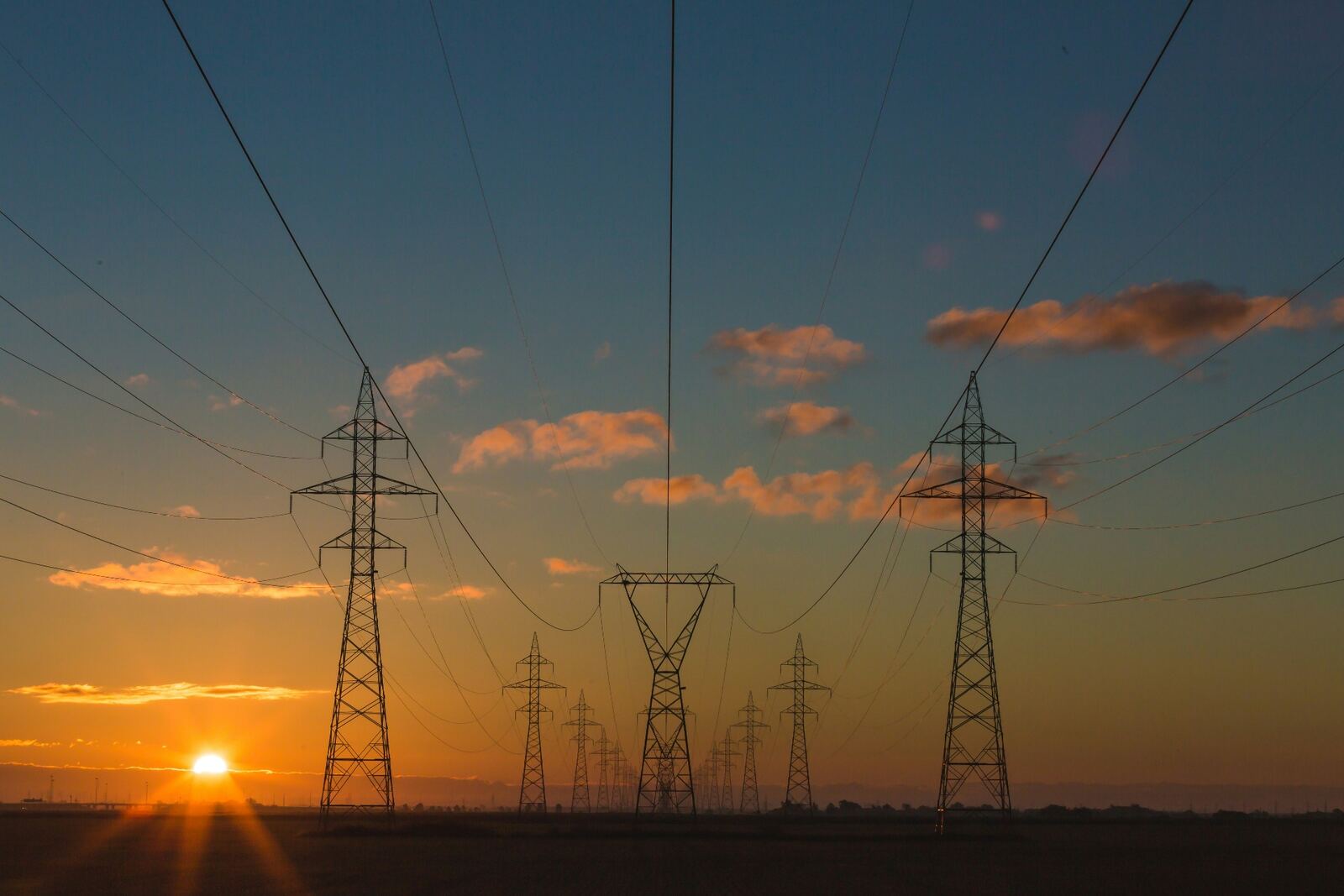 Electricity transmission pylons at sunset — coordinated programme delivery at scale.