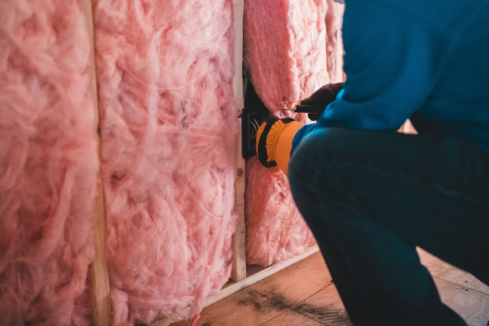 Close-up of fresh mineral wool insulation laid between wooden joists in a bright attic.